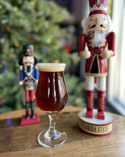 Nutcracker Ale in a stemmed glass between two nutcracker figures