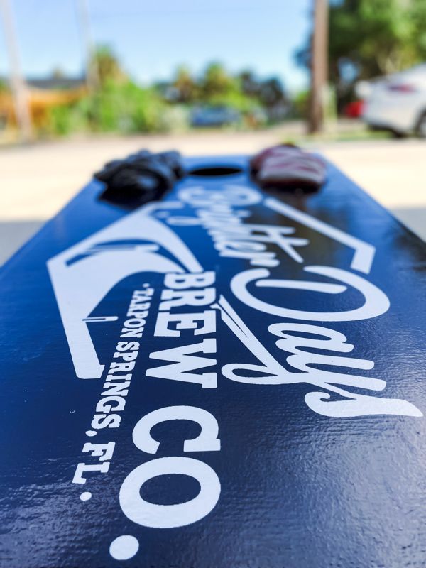Navy cornhole board with the Brighter Days Brew Co. Tarpon Springs logo